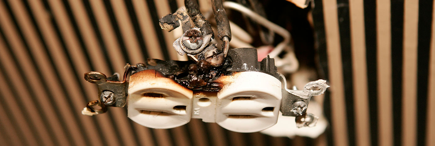 Photo of an outlet that has been destroyed due to electrical fire, probably caused by a catastrophic electrical spike.